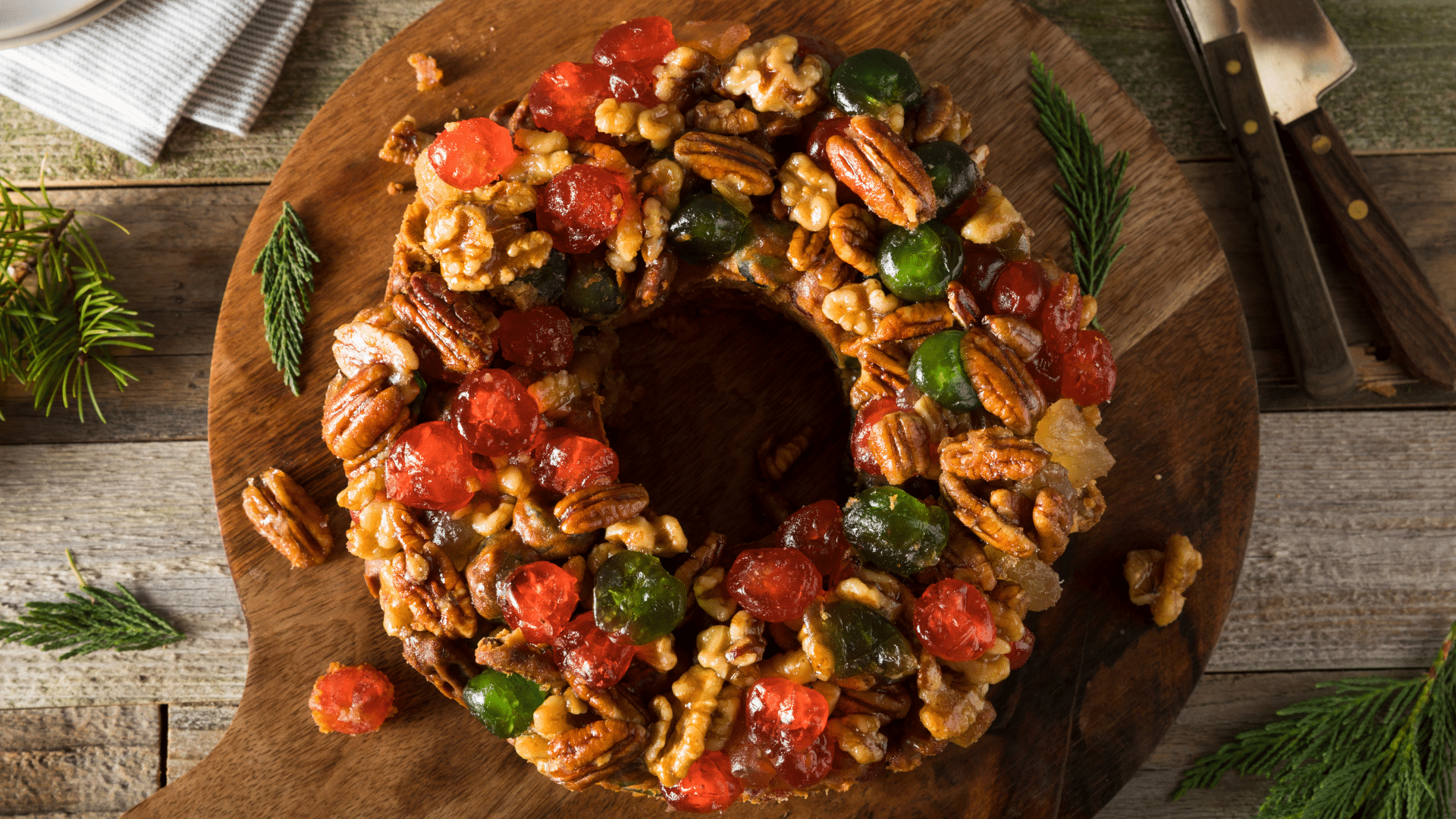 Close-up of a classic Christmas fruitcake packed with colorful dried fruits and nuts, sliced on a rustic wooden table.