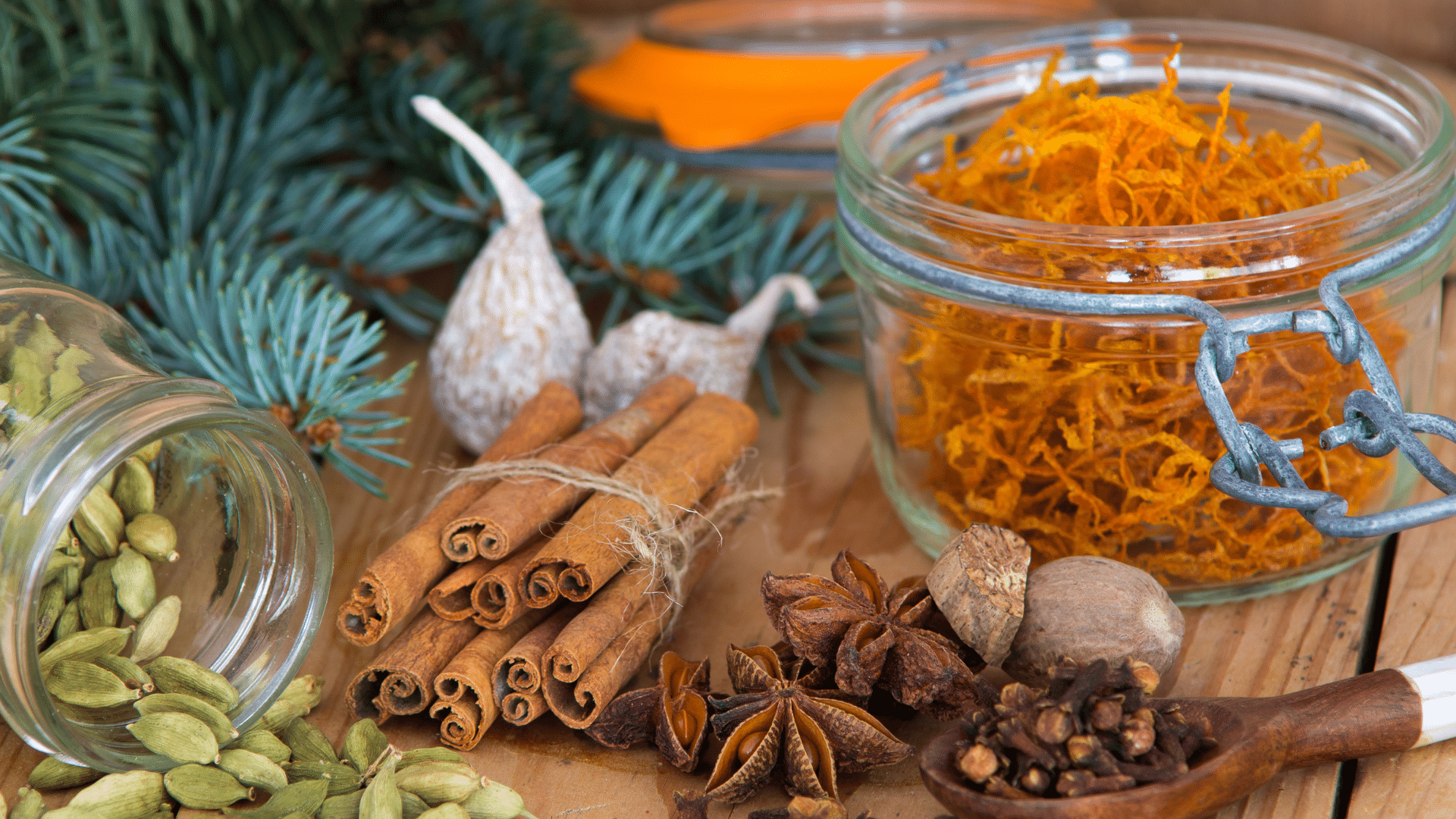 Ingredients for homemade Glühwein including red wine, cinnamon sticks, cloves, star anise, and fresh orange slices arranged neatly.