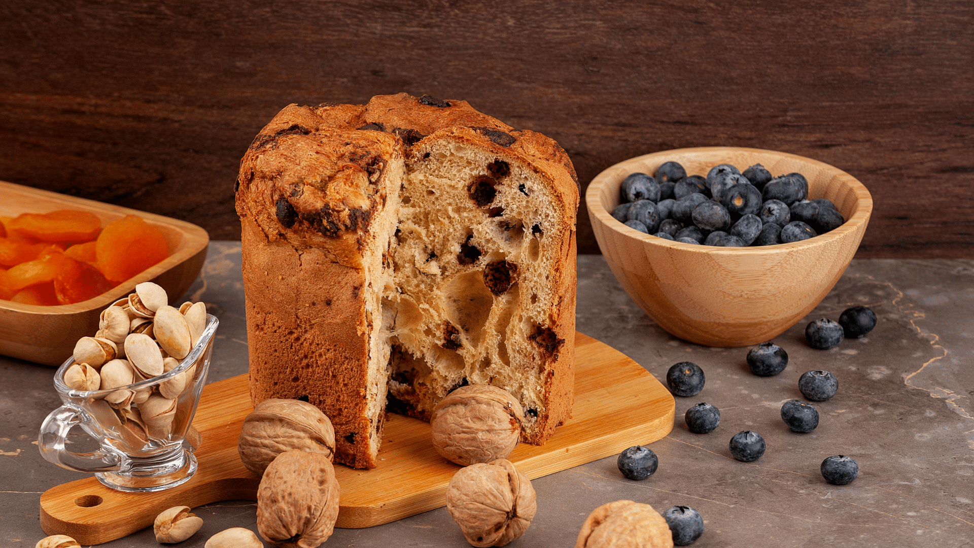 Tall Italian Panettone with a fluffy, airy crumb and citrus peel pieces, pulled apart to show its soft texture.