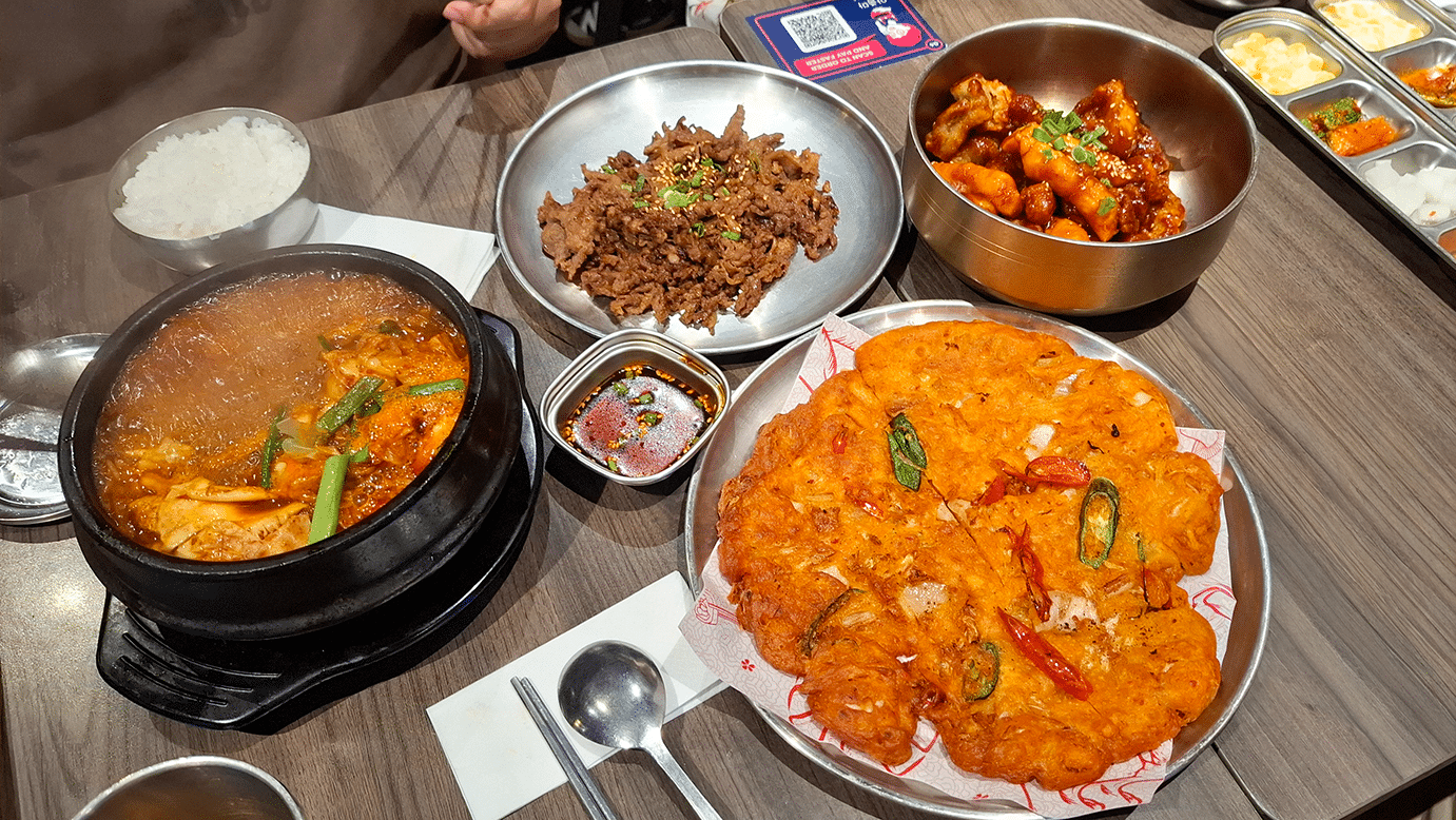 Interior Ajumma’s PLQ with busy dinner crowd, warm lighting, and casual Korean restaurant atmosphere