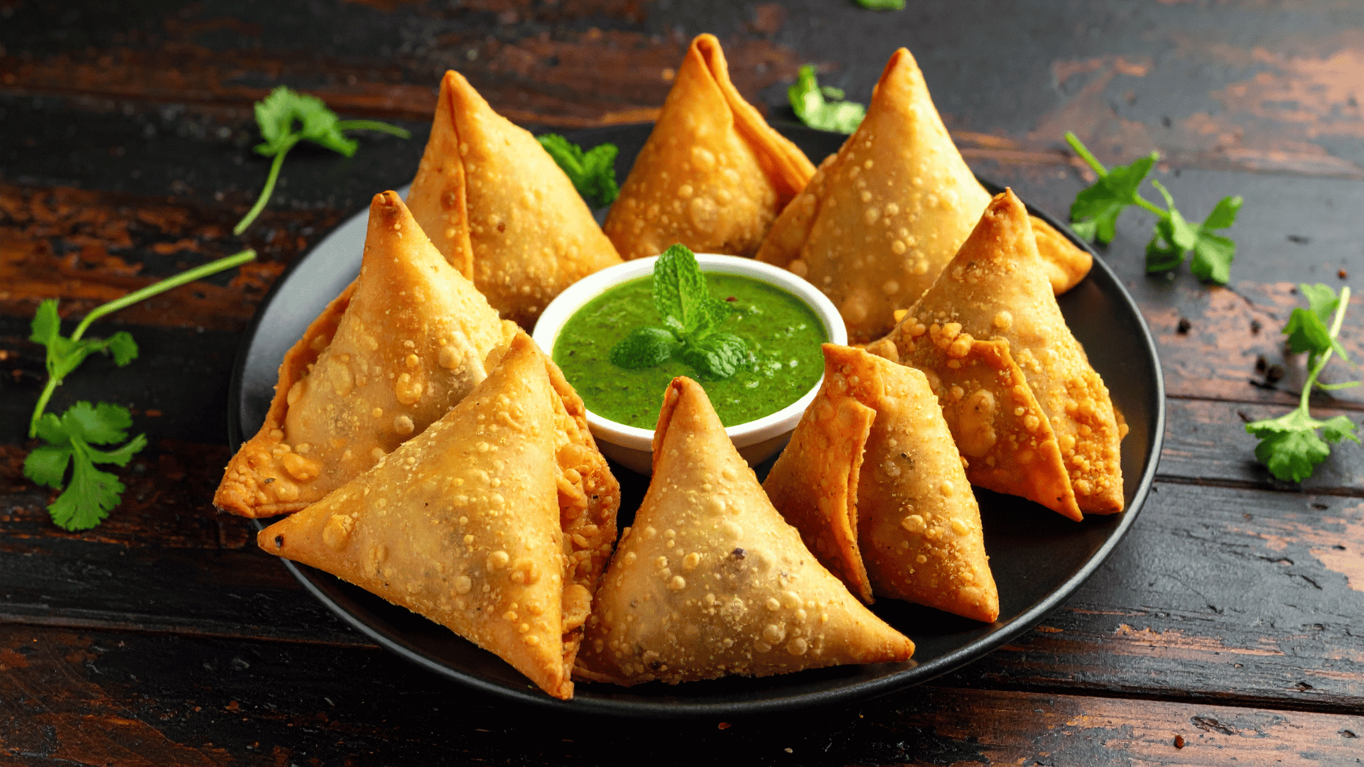 Crispy samosas served with green chutney, a popular savory snack for iftar during Ramadan