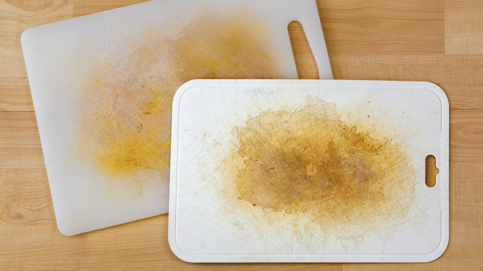 Worn plastic cutting board with yellow stains from frequent use