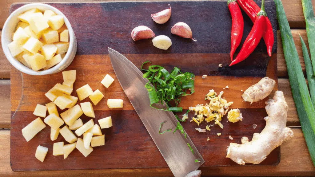 Wooden cutting board filled with fresh kitchen ingredients ready to be chopped