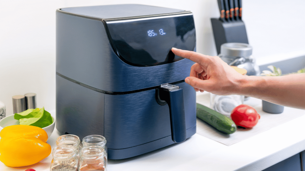 Person using an air fryer in a home kitchen while cooking food with adjustable temperature and timer